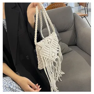 White handmade macramé woven shoulder bag with long fringes held by a person