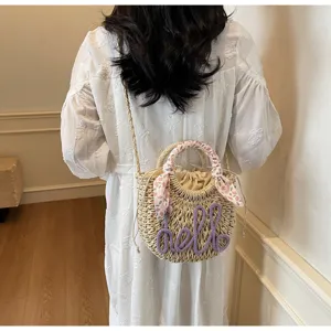 Woven summer straw bucket bag featuring purple hello lettering and floral handle wrap