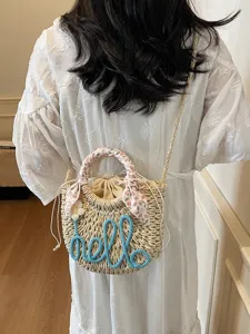 Woven straw bucket bag with 'hello' script worn as a summer beach shoulder bag