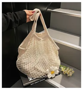 Detailed shot of white mesh tote bag with a decorative knitted flower accessory