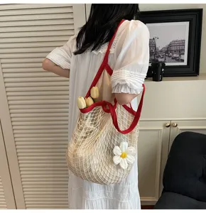 Bohemian crochet mesh tote bag with vibrant red trim and large knitted daisy flower