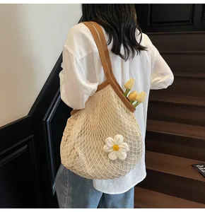 Detail view of a beige mesh tote bag featuring a white knit flower and brown woven straps