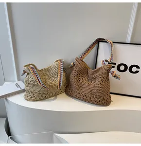 Detailansicht von zwei handgewebten Stroh-Tote-Bags mit bunten Riemen auf Tisch