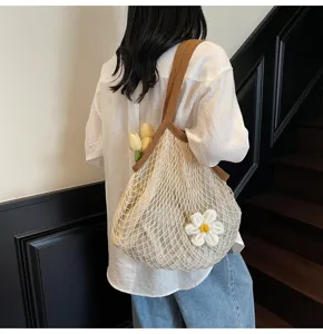Side view of a woven net tote bag with a white flower ornament on a model