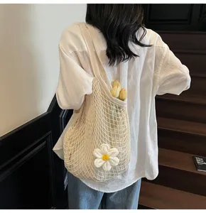 Detailed view of cream crochet mesh tote bag with flower embellishment on model.