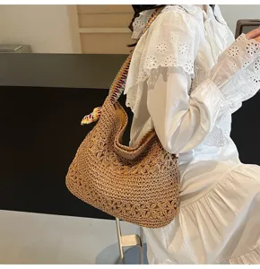 Nahaufnahme einer Stroh-Strandtasche mit Lochmuster und buntem Jacquard-Schultergurt.
