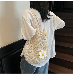 Close-up detail of a white crochet mesh tote bag featuring a large 3D flower charm