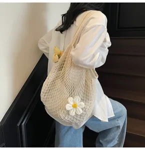 Detailed view of a beige crochet mesh tote bag with a white flower and tulips inside