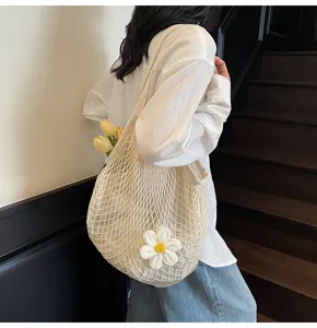 Detail view of the white crochet mesh tote bag with a knit flower being worn by a person.