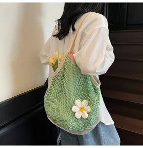 Detailed view of a green mesh hollow tote bag with a white flower decoration for summer