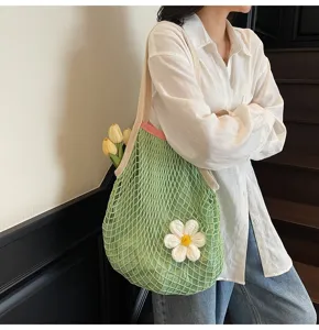 Detail view of a green hollowed mesh tote bag with a crochet flower on a shoulder