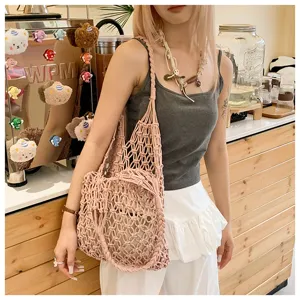 Pink cotton rope woven hollow tote bag shown on model in a cozy cafe setting.