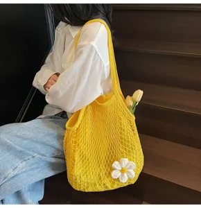 Yellow hollow-out mesh tote bag with white flower charm for beach vacation style.