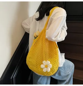 Close-up detail of a bright yellow mesh tote bag featuring a white flower accessory