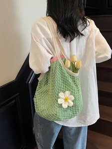Stylish green crochet net tote bag with white flower detail for seaside vacations.