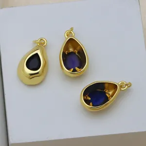 Gros plan détaillé de trois pendentifs gouttes dorés avec des pierres de zircone de couleur.