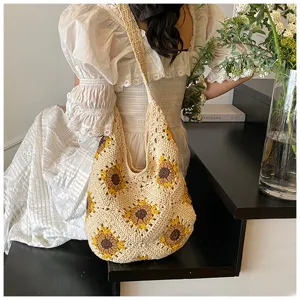 Lifestyle view of a handmade sunflower crochet shoulder bag paired with a white lace dress.