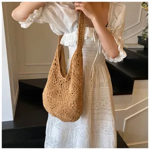 Detail shot of a handmade brown crochet cotton woven shoulder bag worn with a white dress.