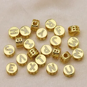Macro view of gold round beads with rhinestone-studded English letters for DIY