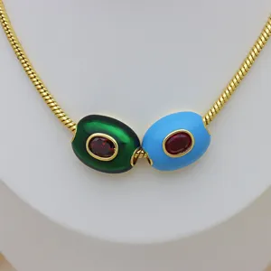 Nahaufnahme von grünen und blauen Fassperlen mit roten Zirkon-Inlays an einer goldenen Kette.