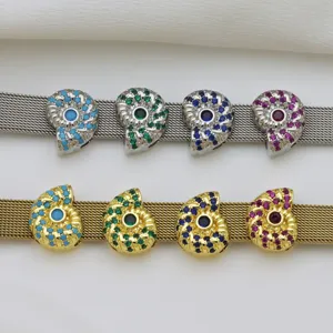 Gros plan pendentif coquillage zircon, pierres colorées sur bracelet montre mesh accessorio détail.