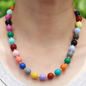 Détail de collier de perles colorées avec des perles rondes et des intercalaires dorés.