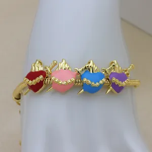 Gold snake chain bracelet with colorful enameled dagger pierced heart charms for women detail view.