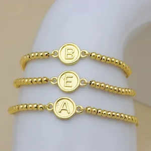 Vista di dettaglio del bracciale di perle dorate con ciondolo a lettera, gioiello fashion.