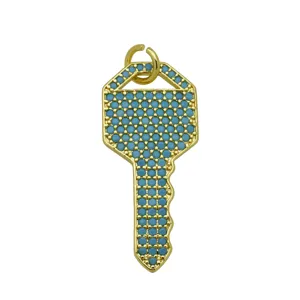 Vista detallada exquisita de un colgante de llave dorado con pequeñas piedras azul turquesa