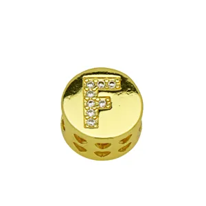Macro view of a gold round charm featuring a crystal-inlaid letter F and heart cutouts
