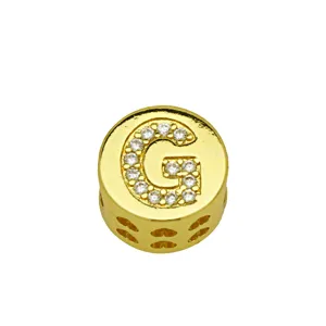 Detailed macro view of gold-plated round charm with crystal letter G and side heart cutouts