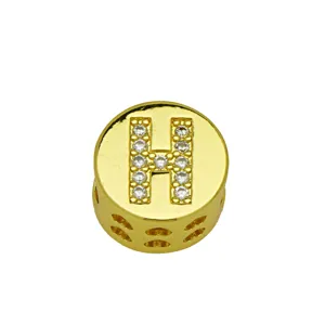 Close-up of a gold-plated round charm with a crystal-encrusted letter H and heart cuts