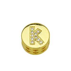 Detailed macro view of gold-plated circular charm with crystal-encrusted letter K