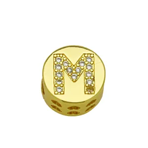 Detailed view of a polished gold circular charm bead with micro-pave letter M design
