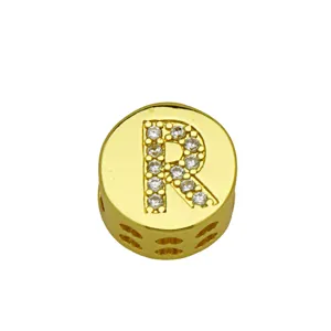 Close-up detail of a gold round charm bead with a rhinestone-encrusted capital letter R