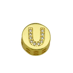 Macro detail of a gold-plated circular charm featuring a crystal-inlaid letter U design