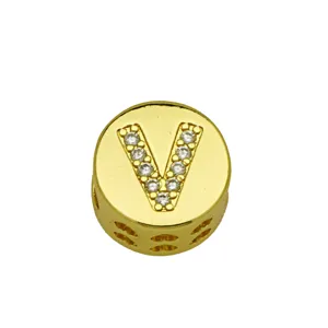 Macro view of gold round pendant with letter V and inlaid stones for DIY jewelry
