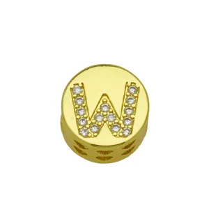 Detailed macro view of a gold-plated round jewelry charm featuring the letter W in crystals