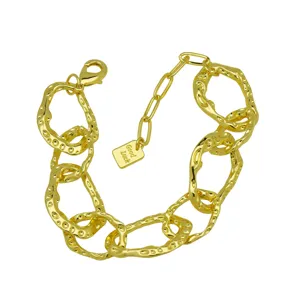 Gold-plated chunky chain bracelet detail, featuring irregular links and a small lucky tag.