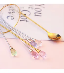 Close-up detail of long stainless steel stirring spoons with sparkling crystal teardrop pendants.
