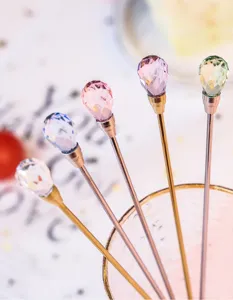 Detail view of crystal cocktail stirring spoons with colorful gemstone toppers and metal handles.