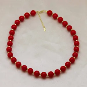Vue détaillée d'un collier de perles rouges avec des perles d'espacement dorées et une chaînette.