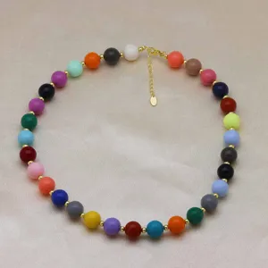 Détail de collier de perles colorées avec des perles rondes multicolores et des intercalaires.