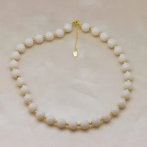 Élégant collier de perles blanches avec des entretoises en métal doré, bijou élégant.