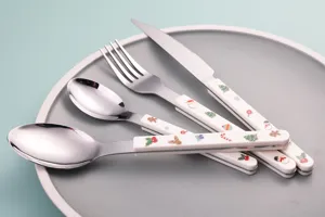 Detail shot of stainless steel Christmas cutlery set with cute holiday print handles on plate.