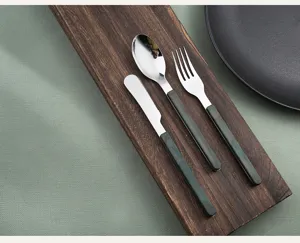Detailed shot of stainless steel cutlery set with dark marble handle on wooden tray.