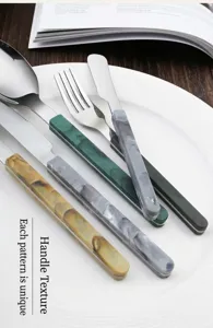 Stainless steel cutlery set detail featuring elegant marble pattern handles on white plate.