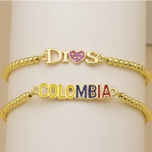Goldfarbenes Perlenarmband Detail mit COLOMBIA und DIOS Buchstaben Anhängern für Damen.