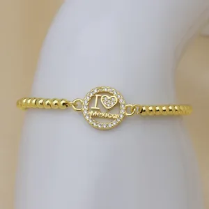 Vergoldetes Perlenarmband mit funkelndem Strass-Kreisanhänger und Mexico-Schriftzug im Detail.