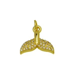 Detalle de colgante de cola de ballena bañado en oro, circonitas brillantes, diseño marino.